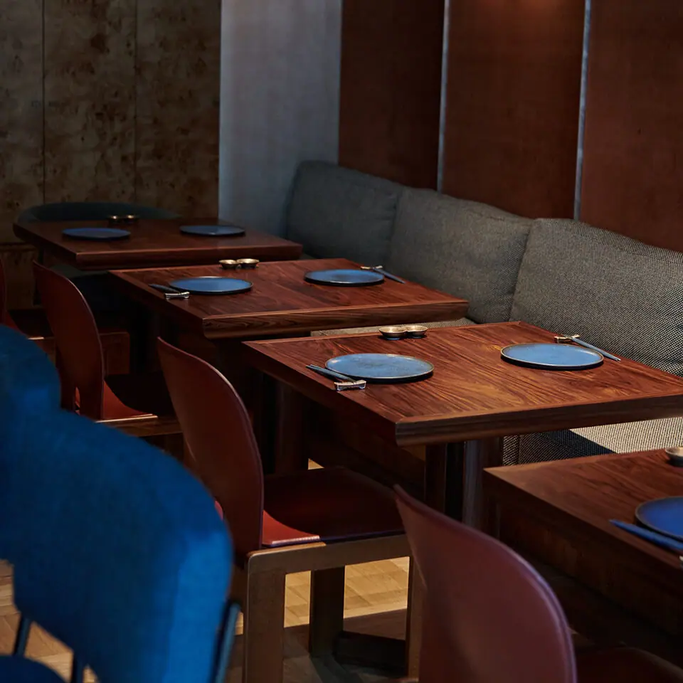 Walnut tables and blue velvet banquettes in the dining room