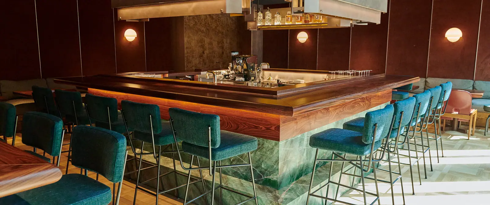 The square bar at uchi with teal velvet stools and a green marble front