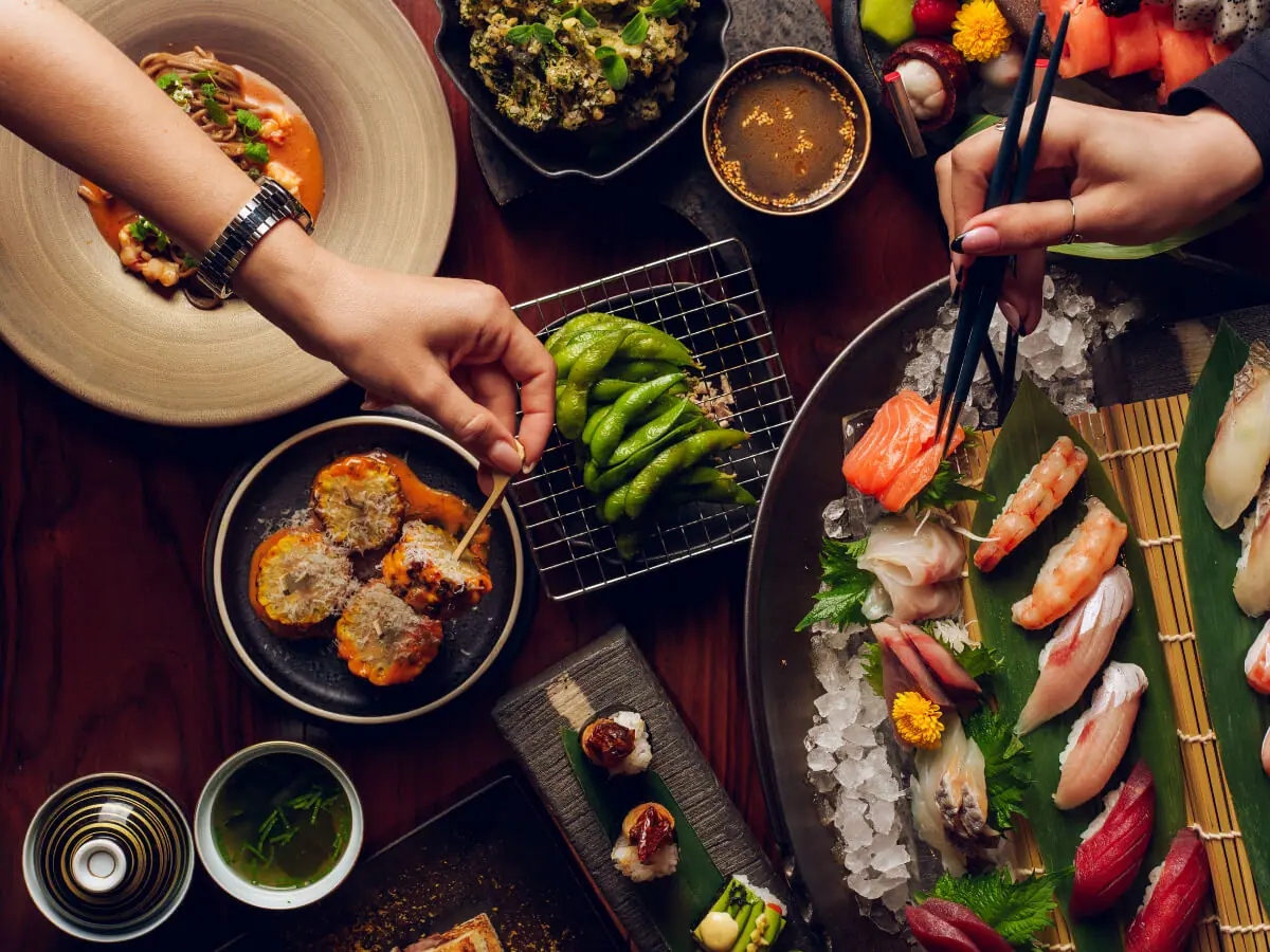 A table of sushi, sashimi, edamame and small plates being shared